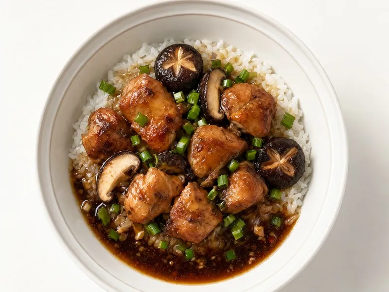 Bowl of soy-braised chicken thighs and shiitake mushrooms over rice.